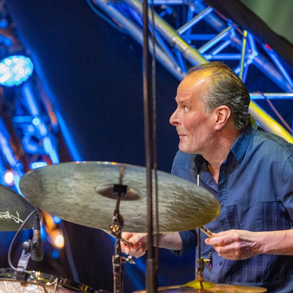 Markku Ounaskari (Kalmari Quartet) soittaa rumpuja värikkäässä valossa