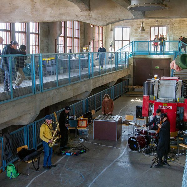 Hota-yhtye esiintyy Rinnerikastamossa, yleisö seuraa esitystä ylhäältä