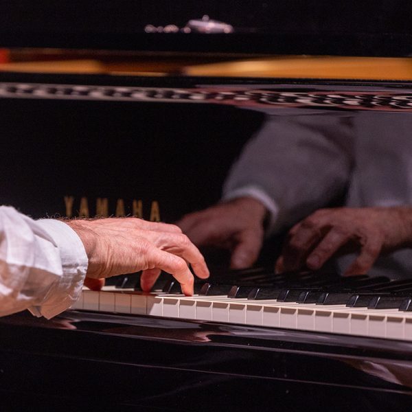 Timo Tuomisen kädet pianon koskettimilla, heijastus flyygelin pinnasta